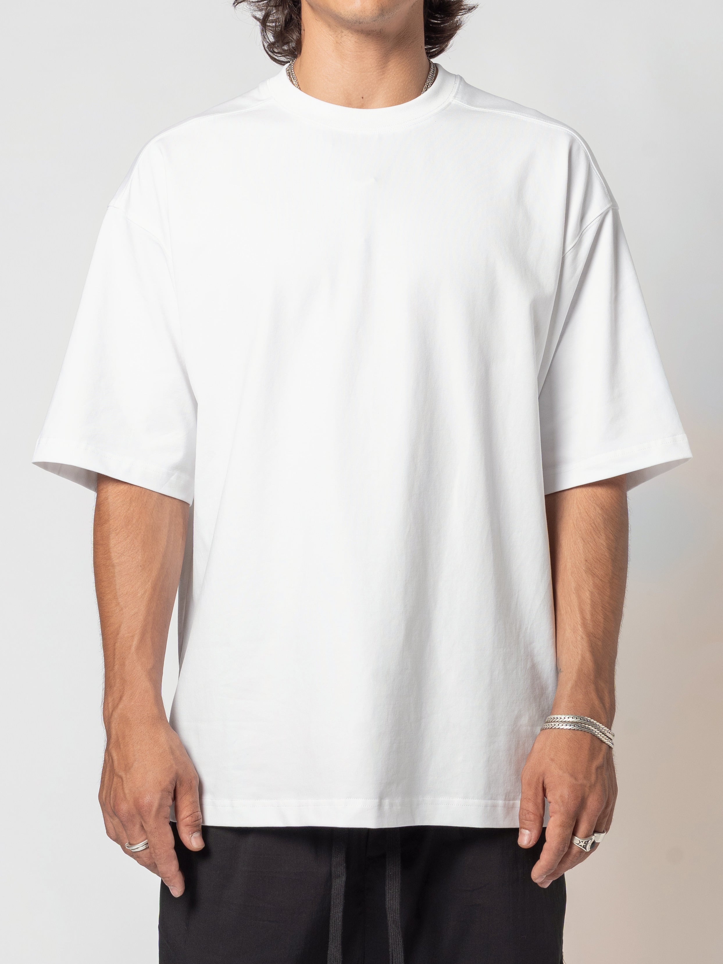 AITO Oversized Cotton T-Shirt in White - front view of the torso, body angled a fraction to one side, arms loose and a silver bangle showing at the wrist