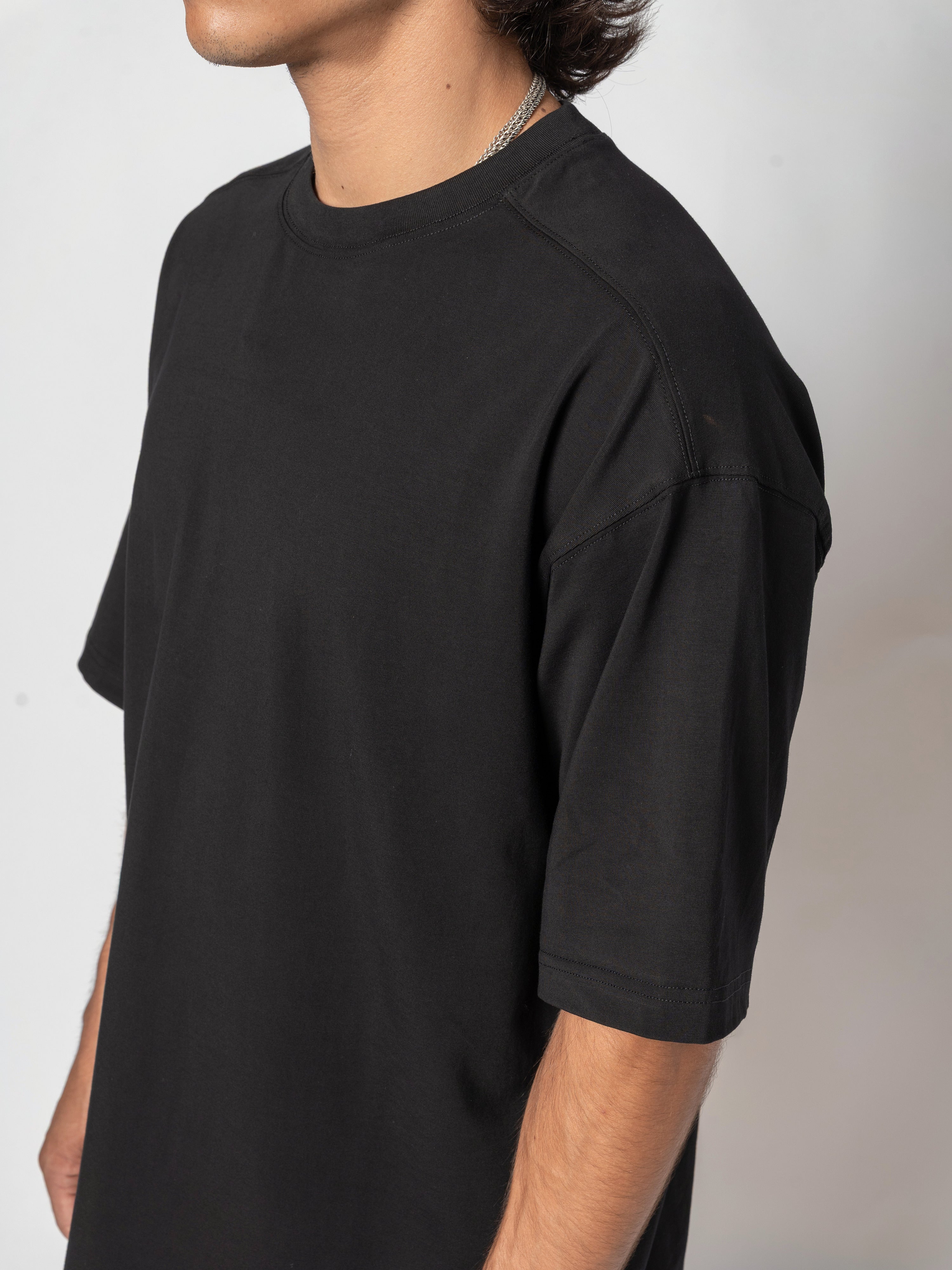 AITO Oversized Cotton T-Shirt in Black - close-up from the side, the shoulder and the whole sleeve filling the frame