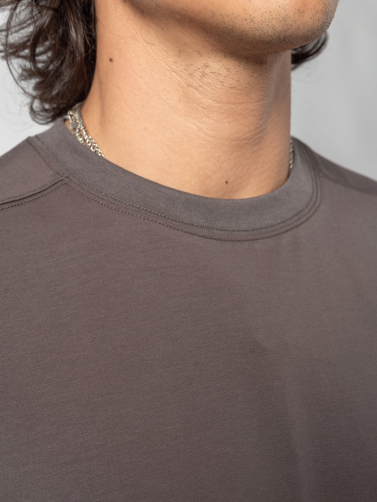 AITO Oversized Cotton T-Shirt in Dark Grey - close on the ribbed crew neckline with a chain resting on the collarbone above it