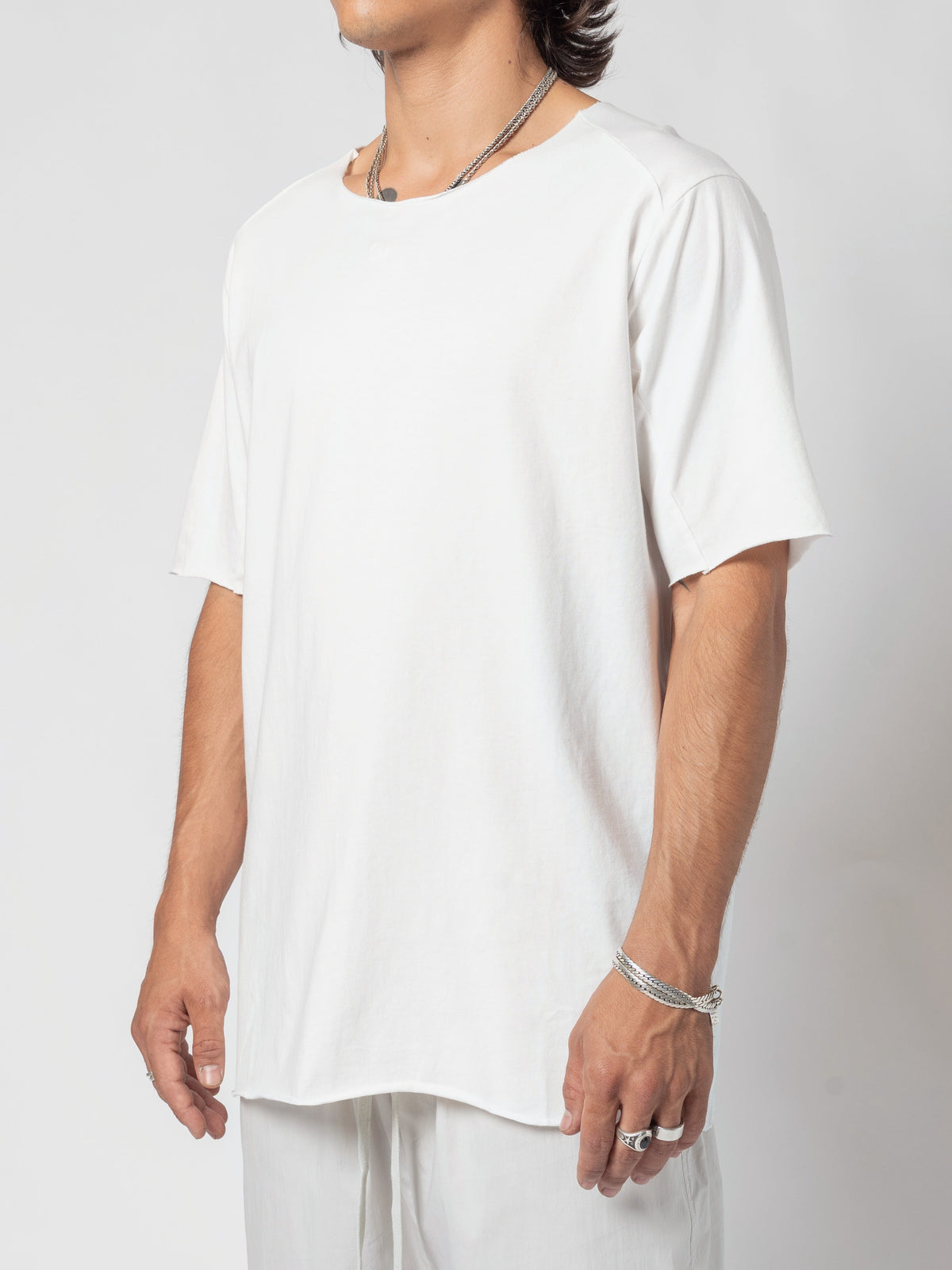 AITO Scar Stitch Cotton T-Shirt in White - three-quarter view of the torso, the arm relaxed at the side and the hem dipping at the seam