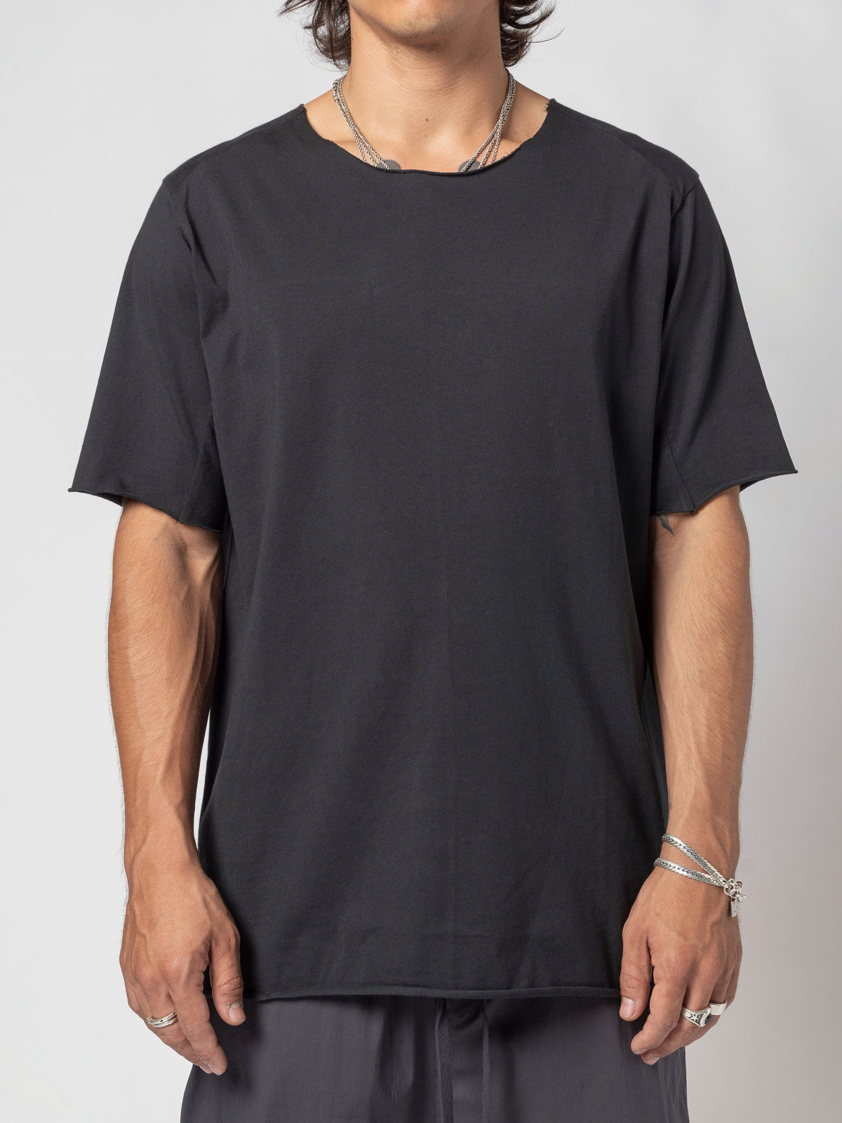 AITO Scar Stitch Cotton T-Shirt in Black - front view of the torso cropped at the jaw, arms resting against the body, hem level over dark shorts