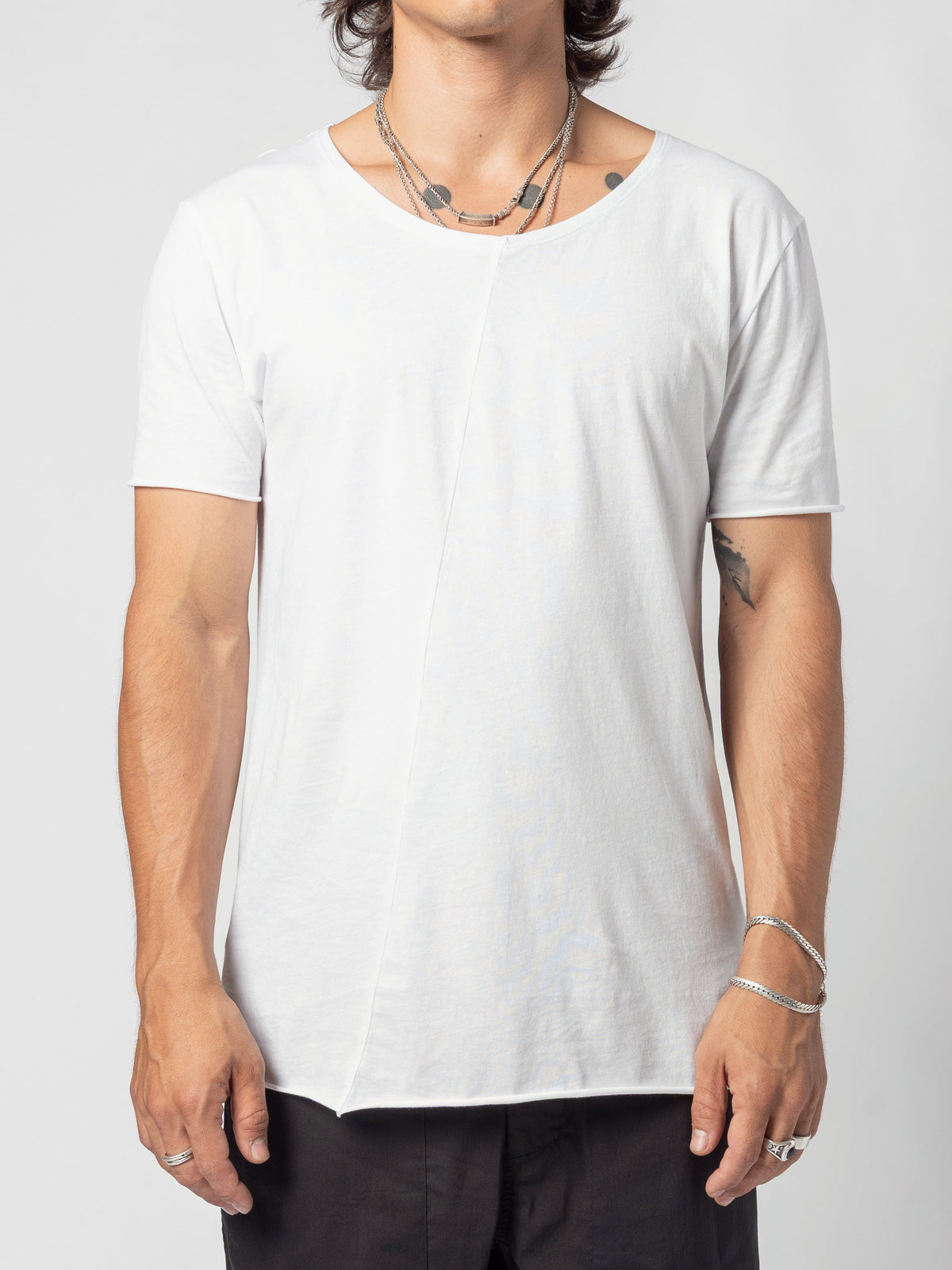 AITO Scoop Neck Cotton T-Shirt in White - front view of the torso, arms at the sides, the curved hem sitting over black trousers