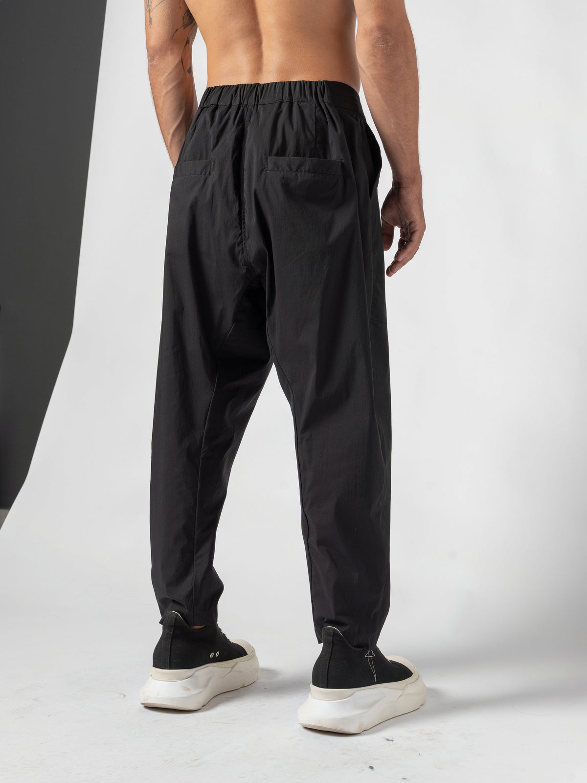 AITO Pleated Drop-Crotch Pants in Black - back three-quarter, the seat turned to camera with one patch back pocket in view
