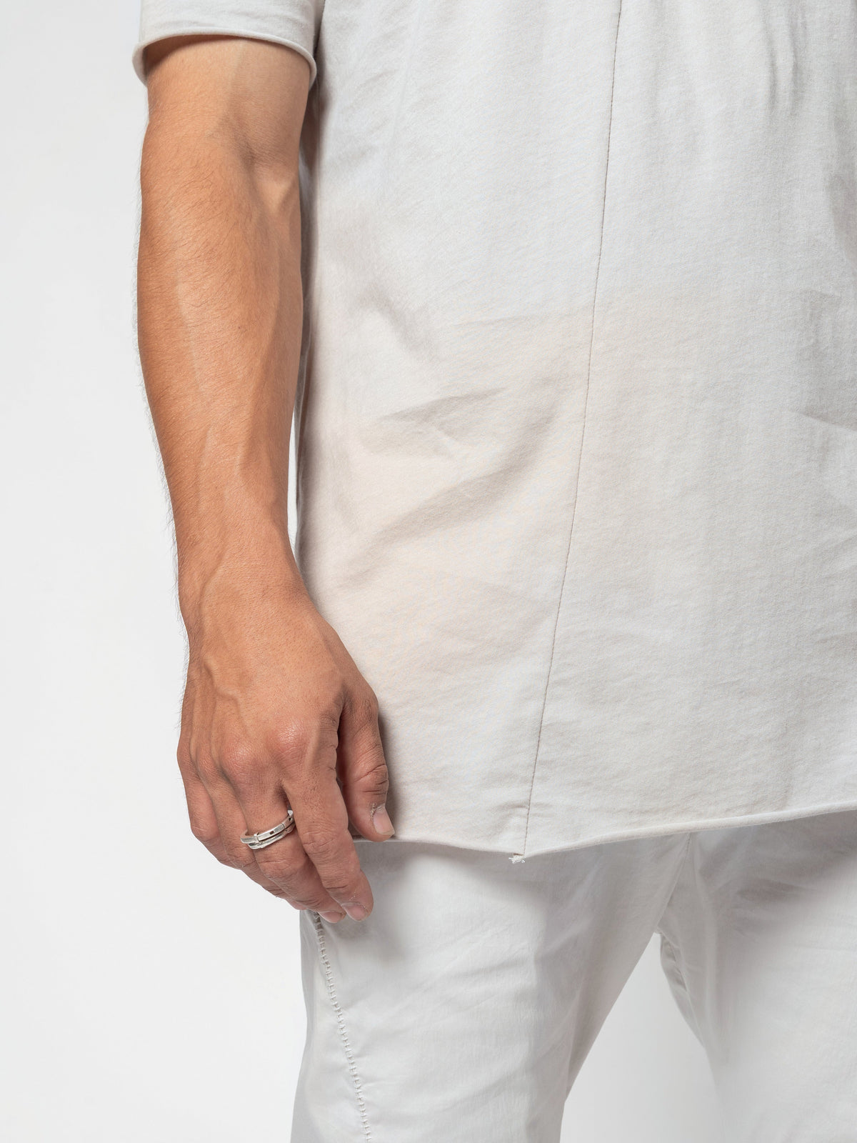 AITO Scoop Neck Cotton T-Shirt in Off White - close-up of the side, the hem falling over the trouser waist with the hand hanging beside it