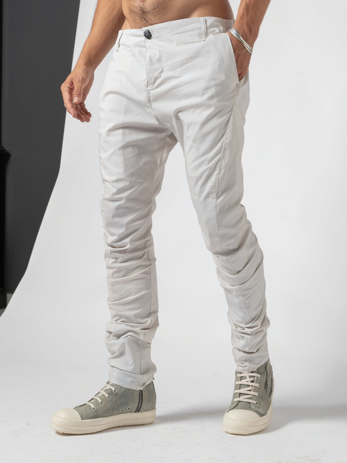 AITO Stacked Hem Slim Pants in Off White - three-quarter front mid-step, a hand in the pocket and the weight on the front leg