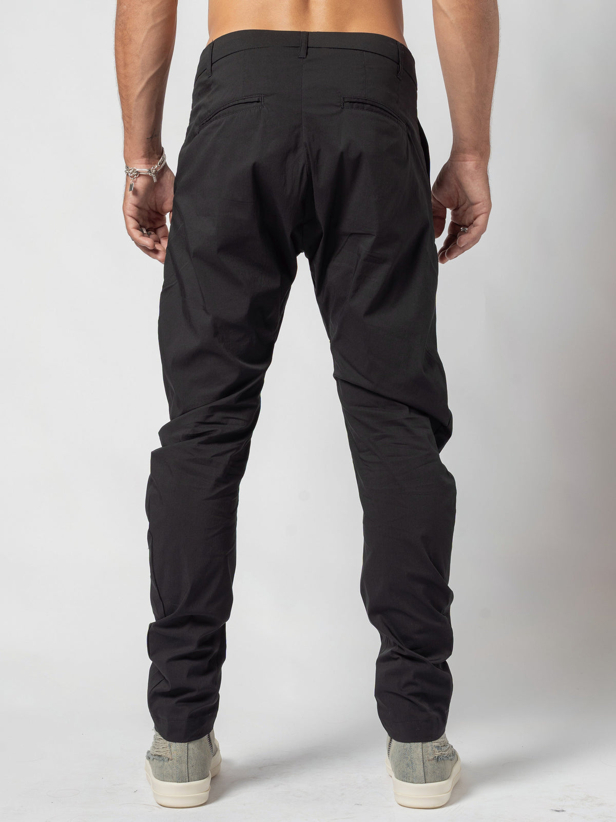 AITO Low-Rise Slim Pants in Black - back view from the waistband down, feet planted apart