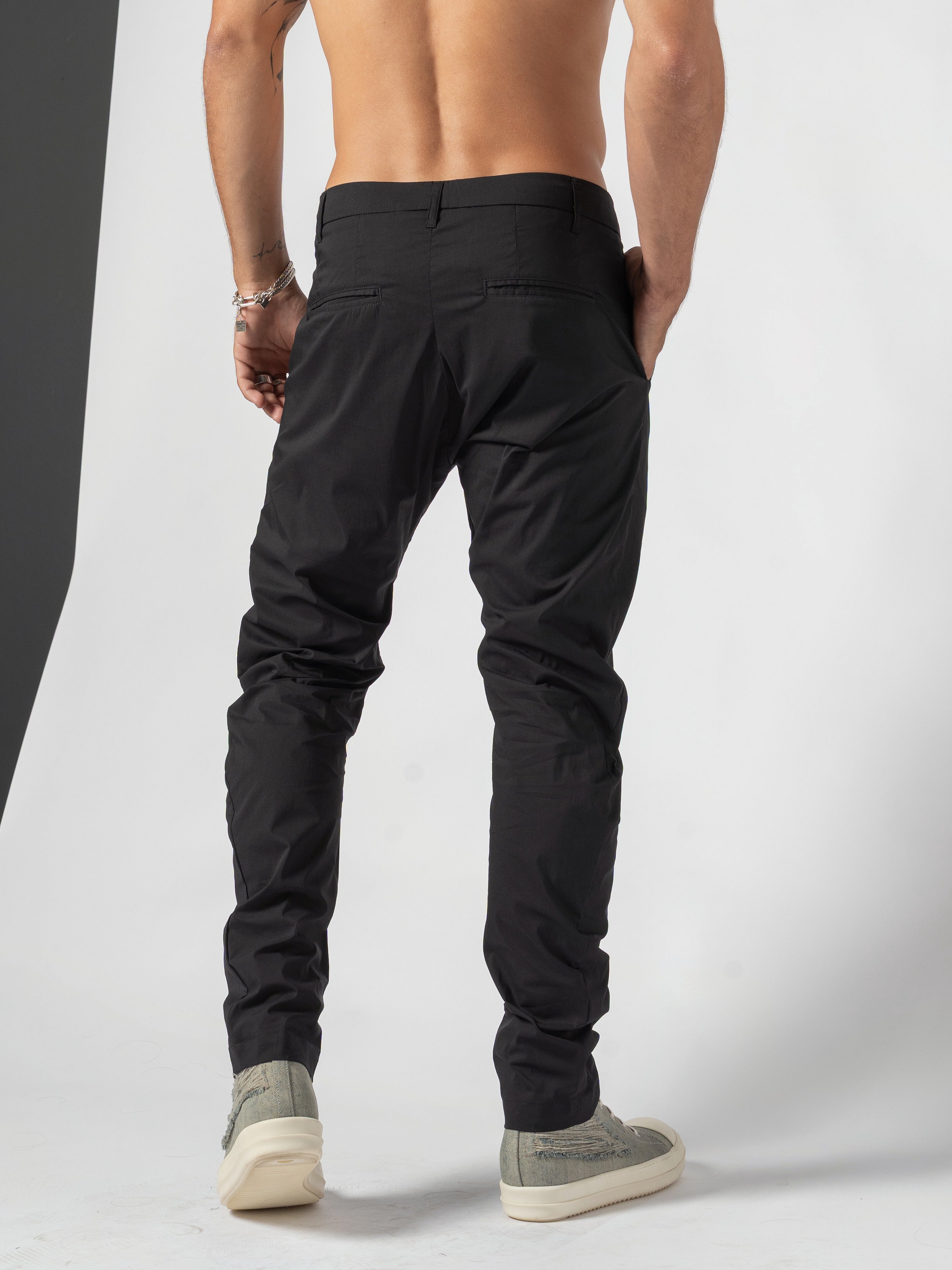 AITO Low-Rise Slim Pants in Black - back view with one hand slipped into the side pocket at the hip